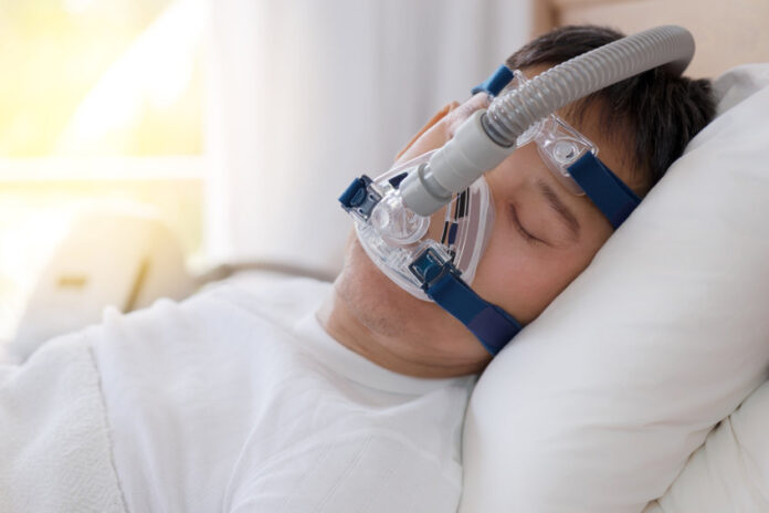sleep apnea therapy, man sleeping in bed wearing cpap mask. heal